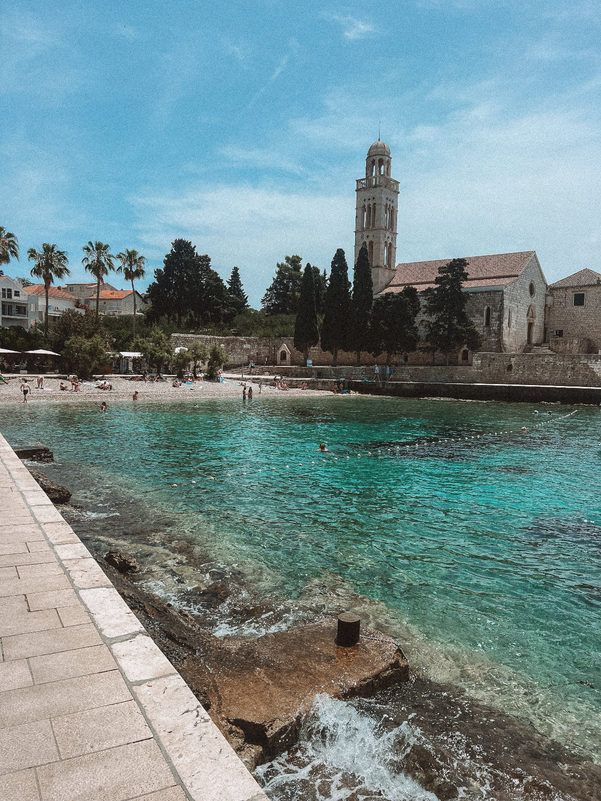 Coastal scene with a church and beach, under a clear blue sky.