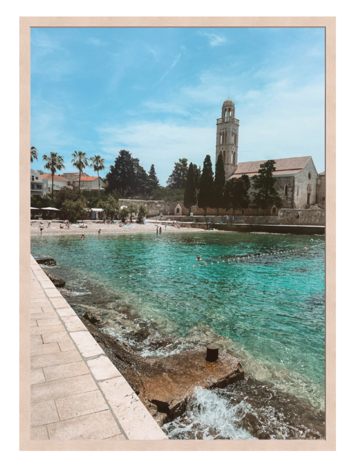Beach scene with turquoise water and a building in the background, framed as a poster.