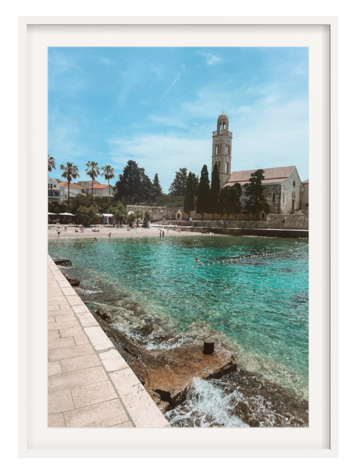 Framed photograph of a coastal scene with a church and clear blue water.