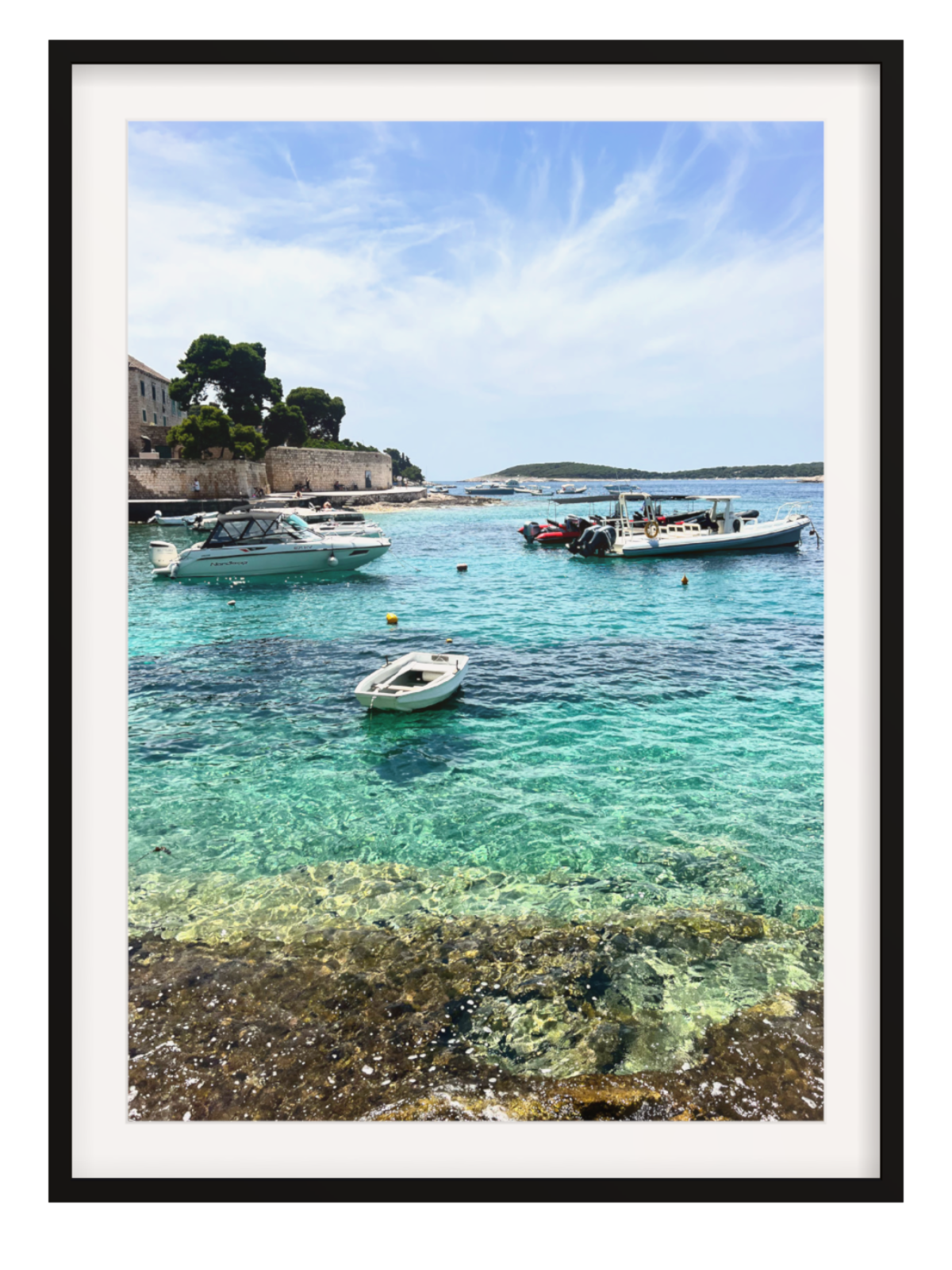 Framed photograph of a coastal scene with boats in clear water.