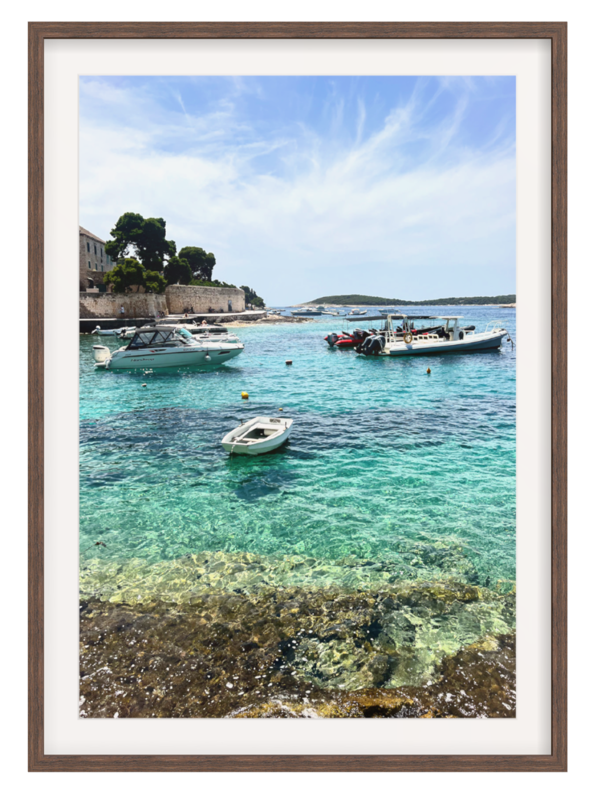 Framed photograph of a coastal scene with boats in clear blue water.
