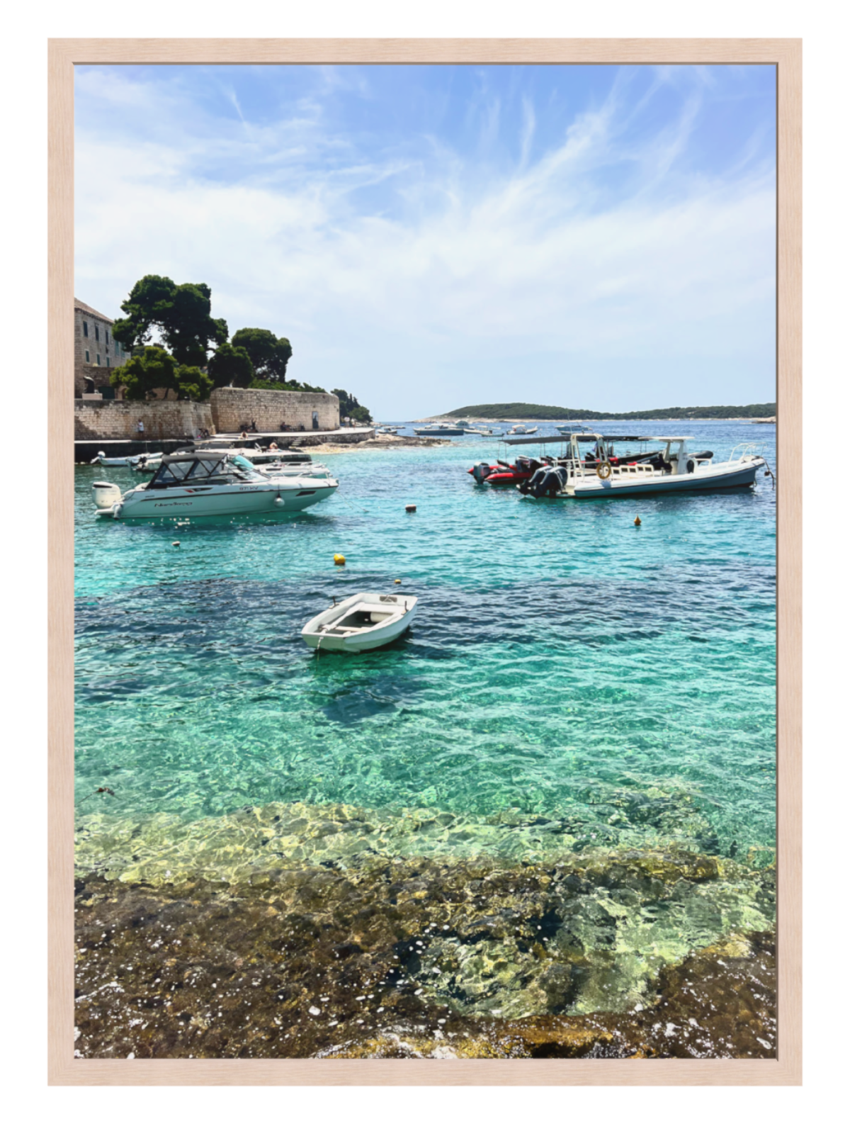 Coastal scene with clear blue water, boats, and a wooden frame.