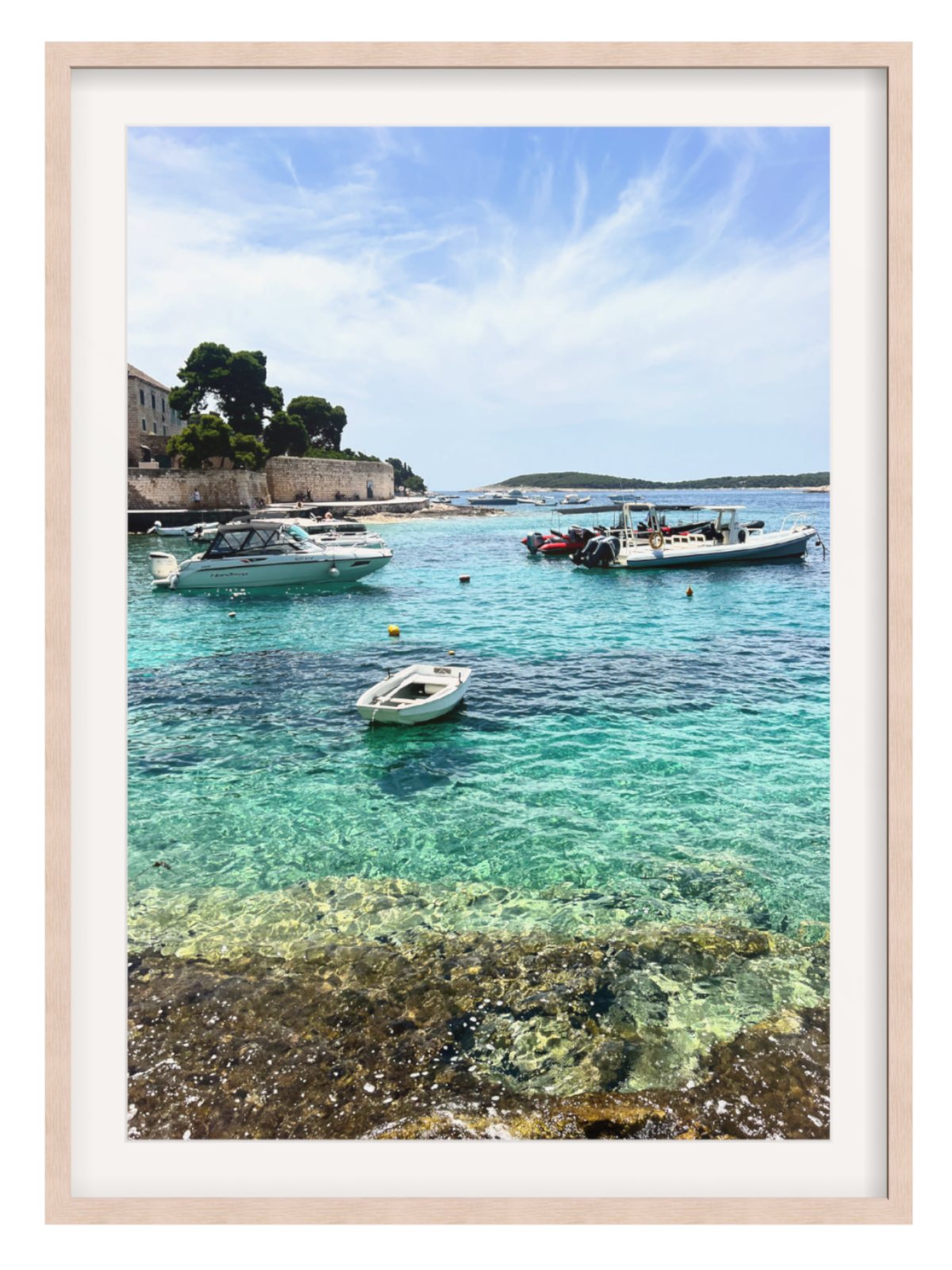 Framed photograph of a coastal scene with boats in clear blue water.