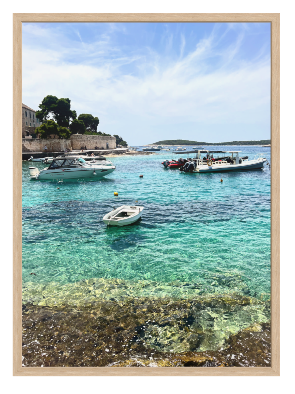 Coastal scene with boats in clear water and a blue sky.