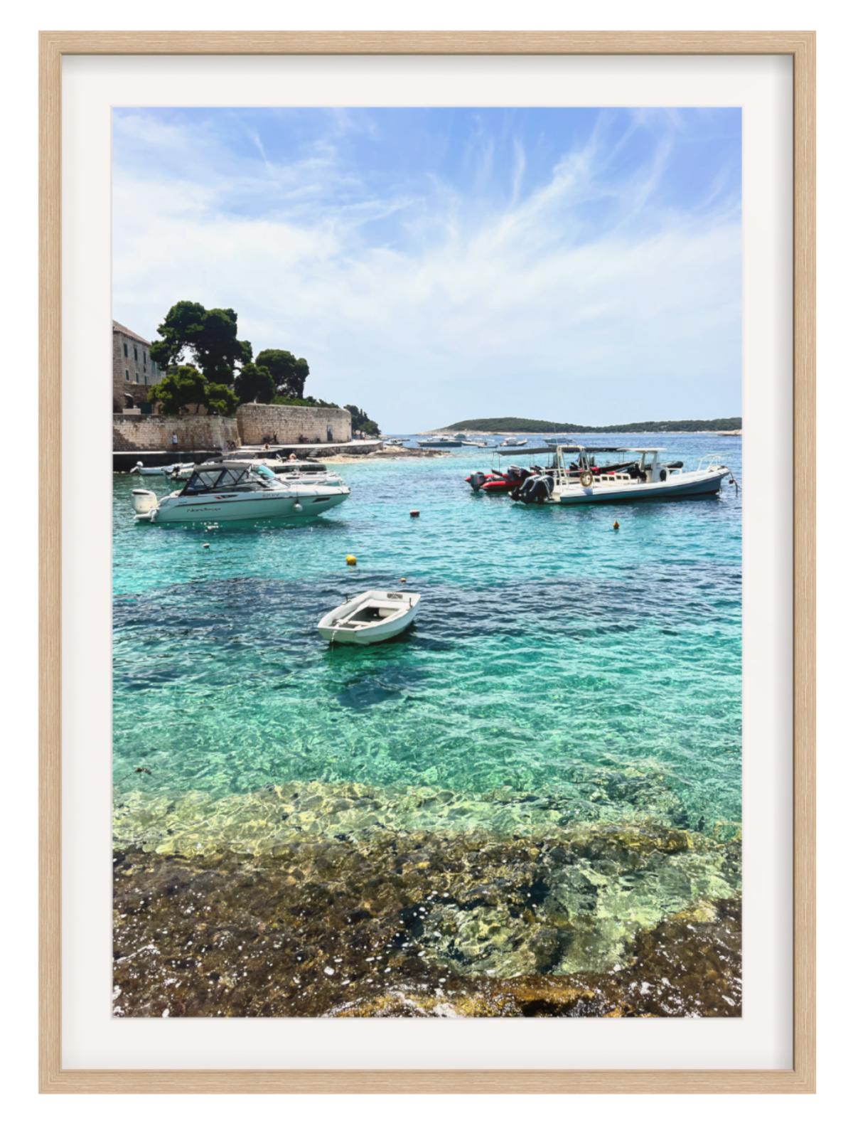 Framed photograph of a coastal scene with boats in clear water.