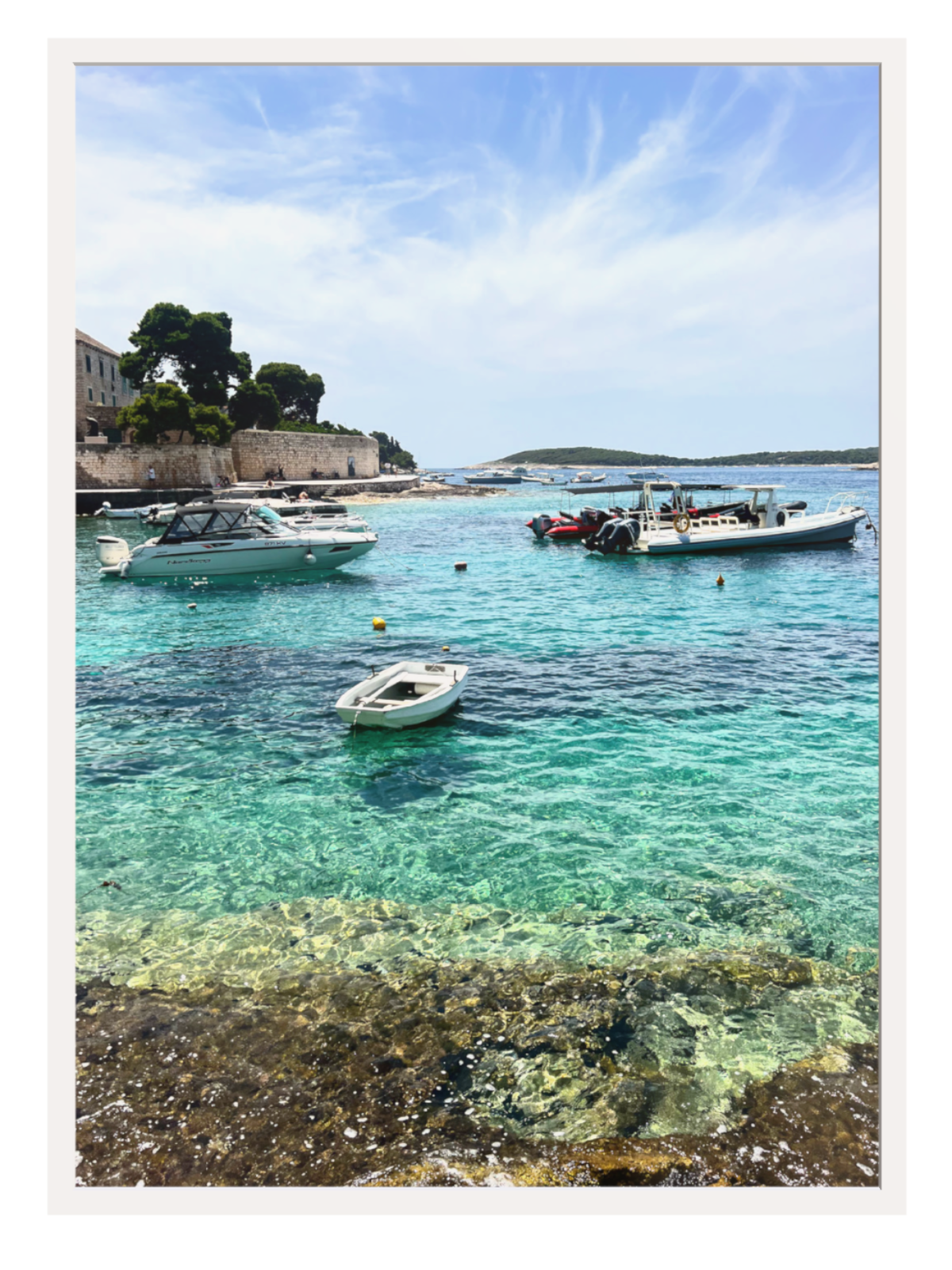 Coastal scene with clear turquoise water, boats, and a blue sky.