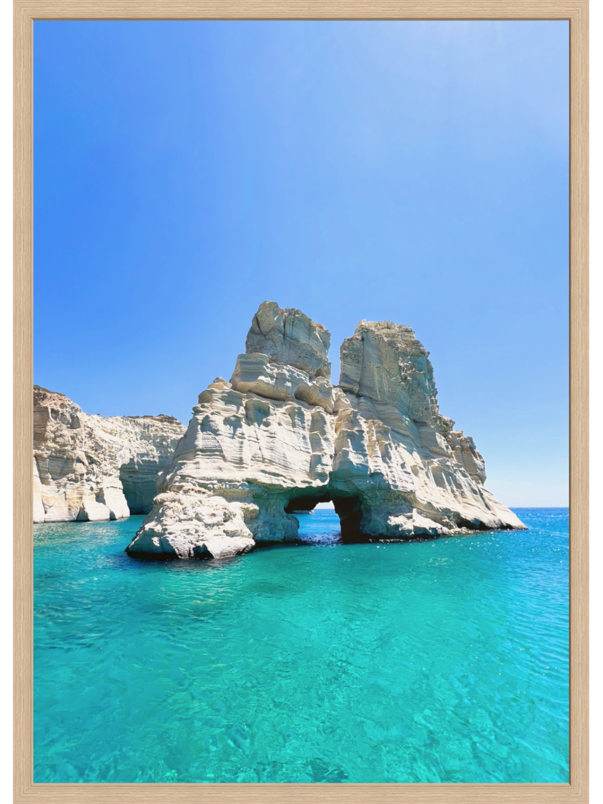 Rock formation with a natural arch over turquoise water under a clear blue sky.