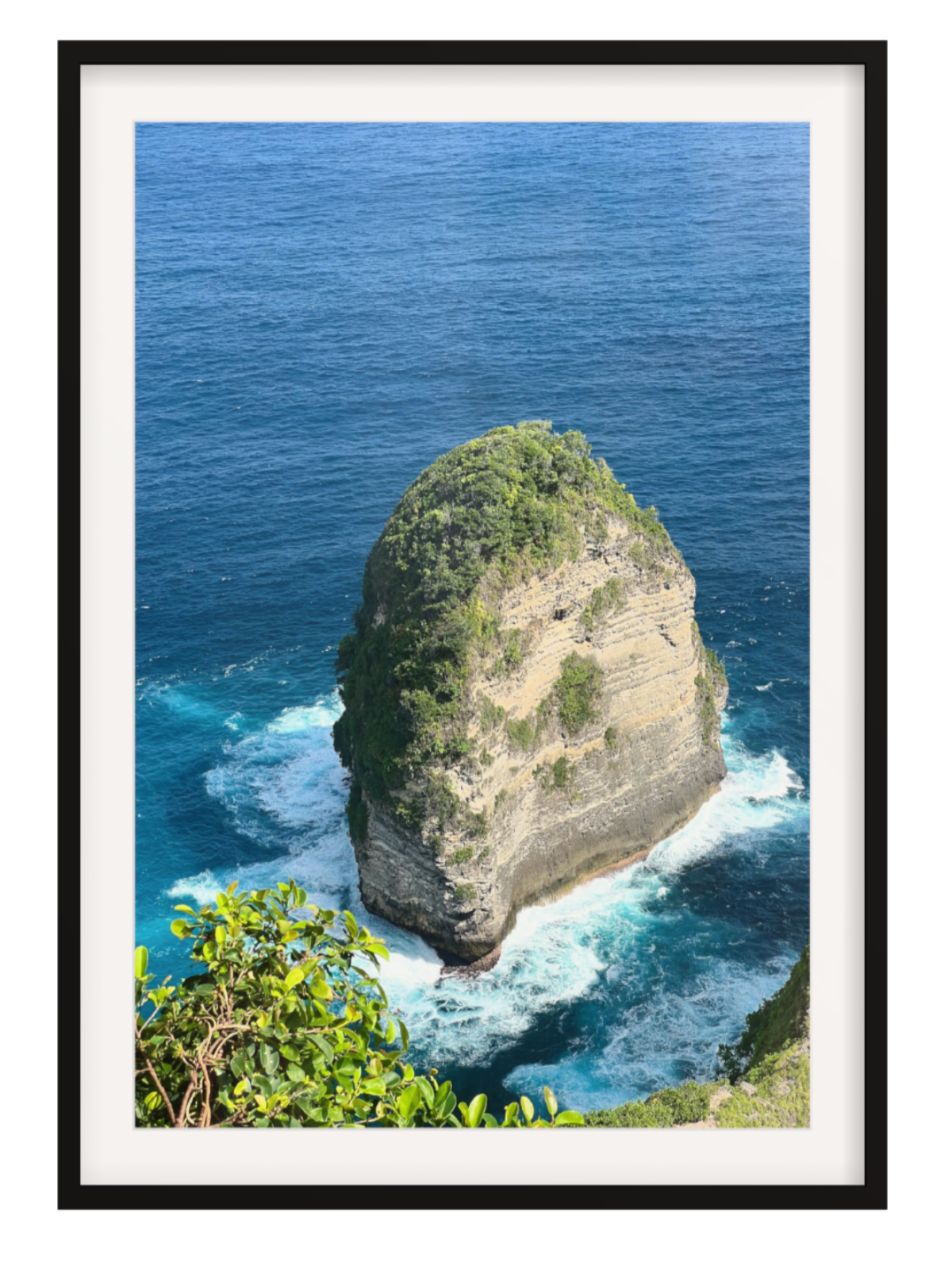 Black Framed photograph of a rocky island with blue ocean and white waves.