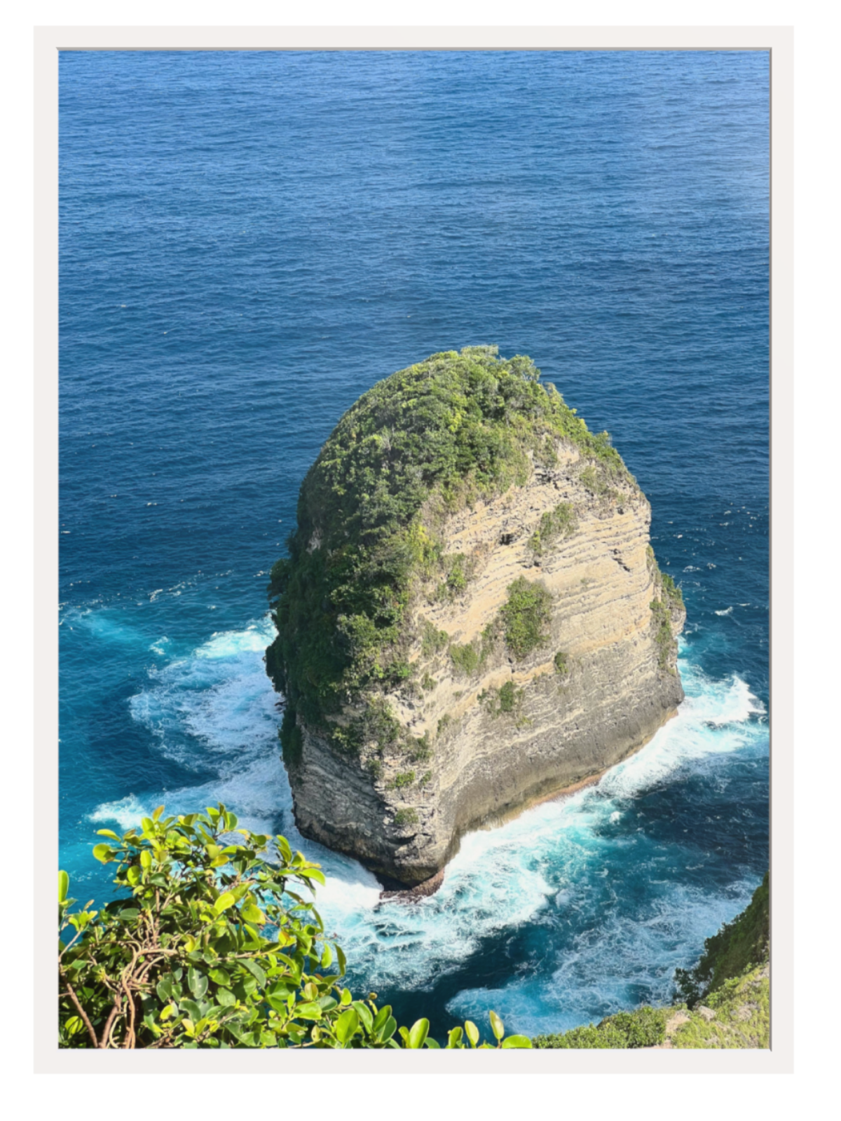 White frame Isolated rock formation in the middle of the ocean with clear blue water.