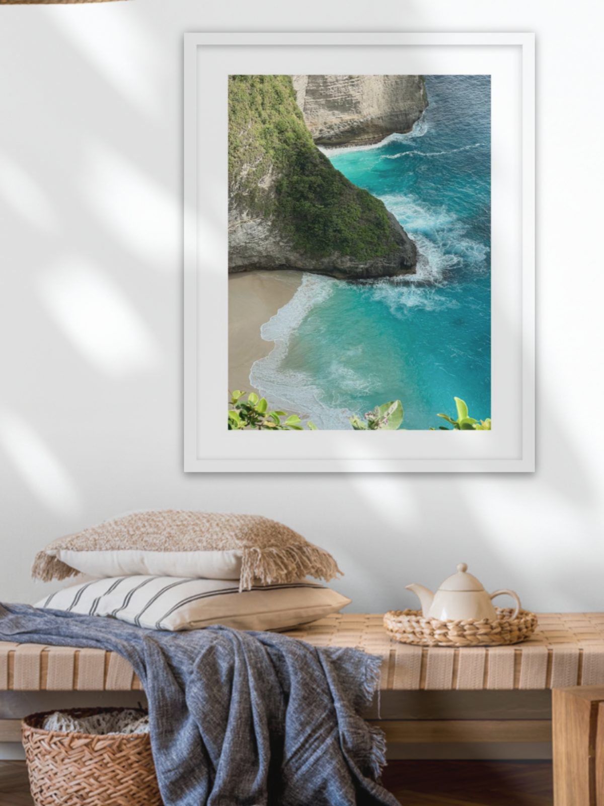Framed photograph of a coastal scene on a wall above a wooden bench.