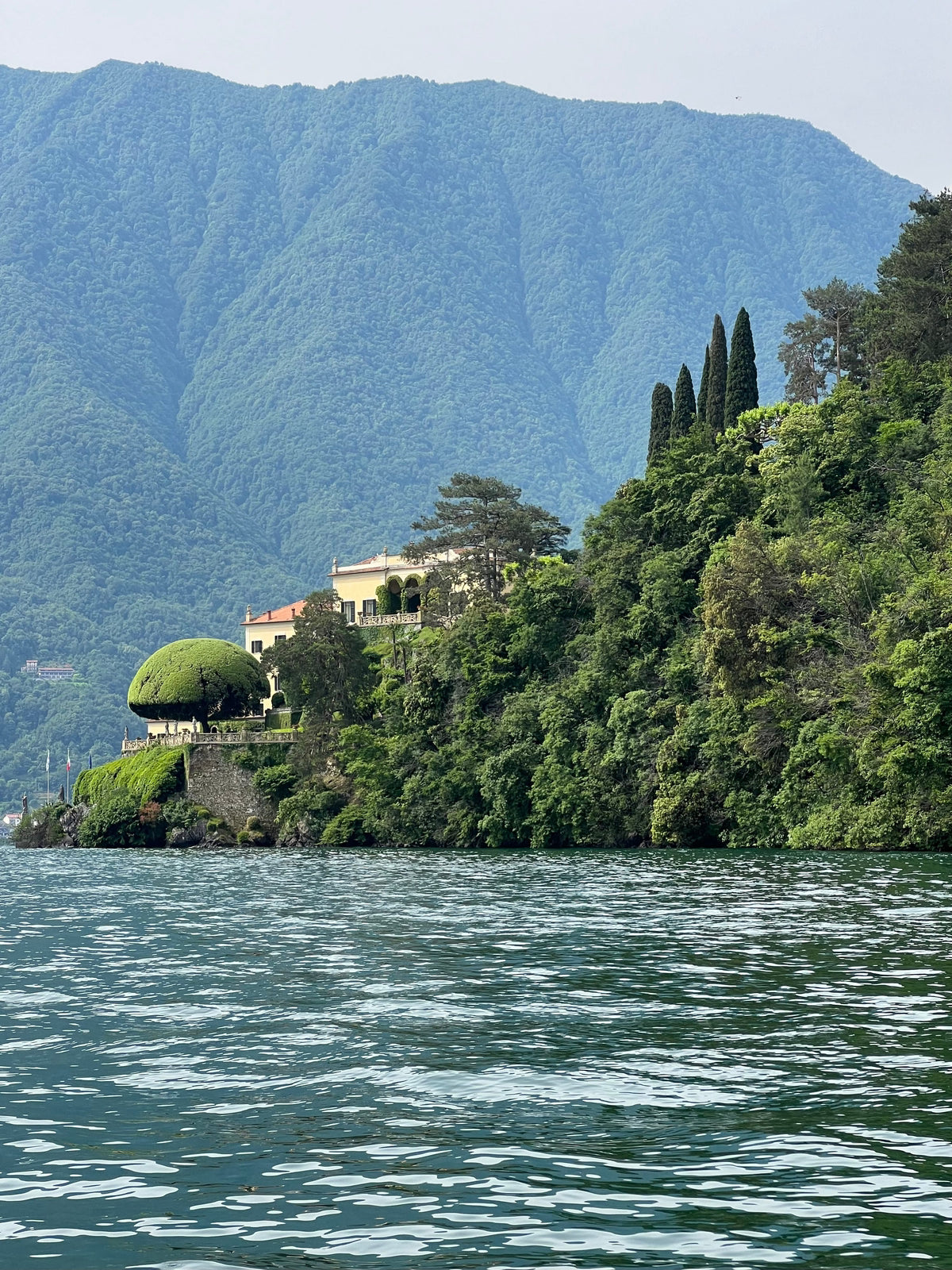Villa on a hillside with mountains and lake in the background