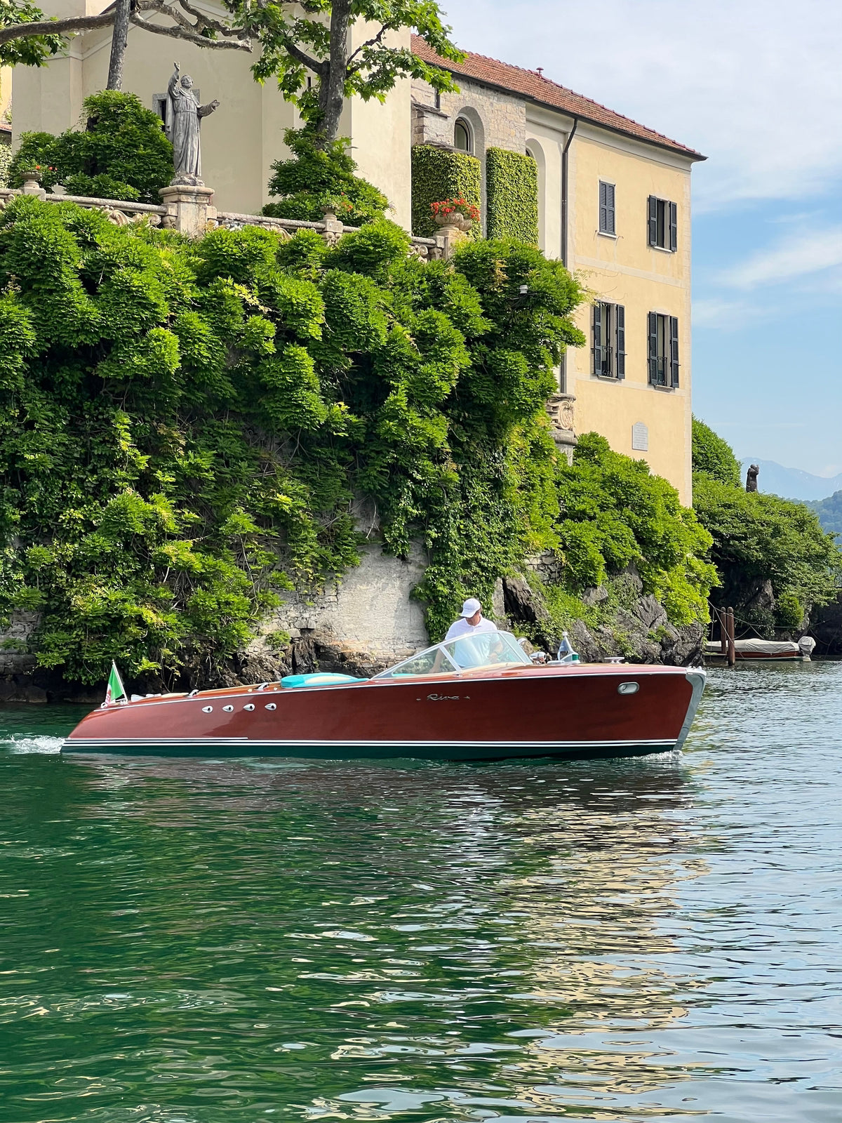 Red boat on a lake with a scenic background of a building and greenery