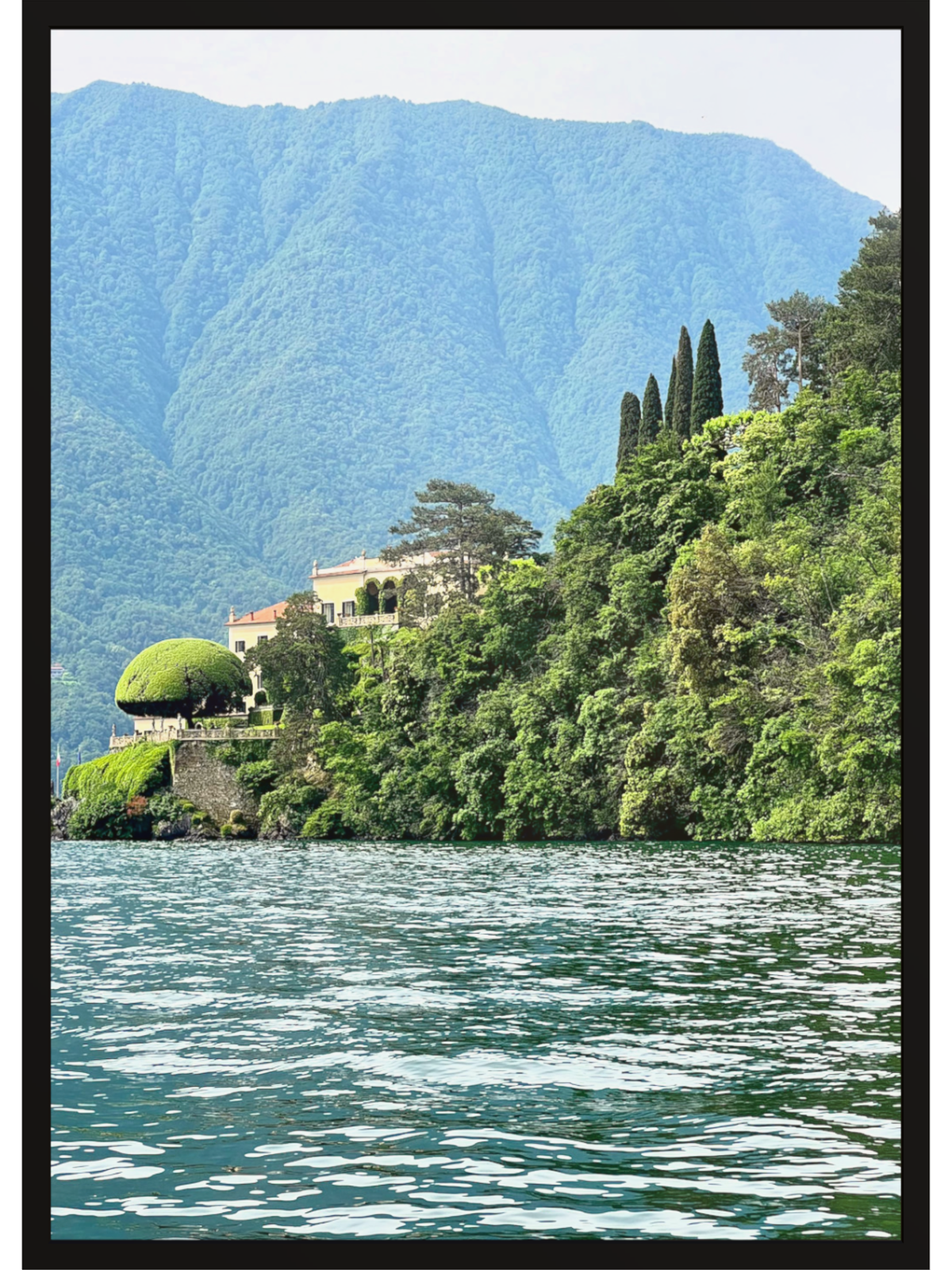 Villa on a hillside overlooking a lake with mountains in the background