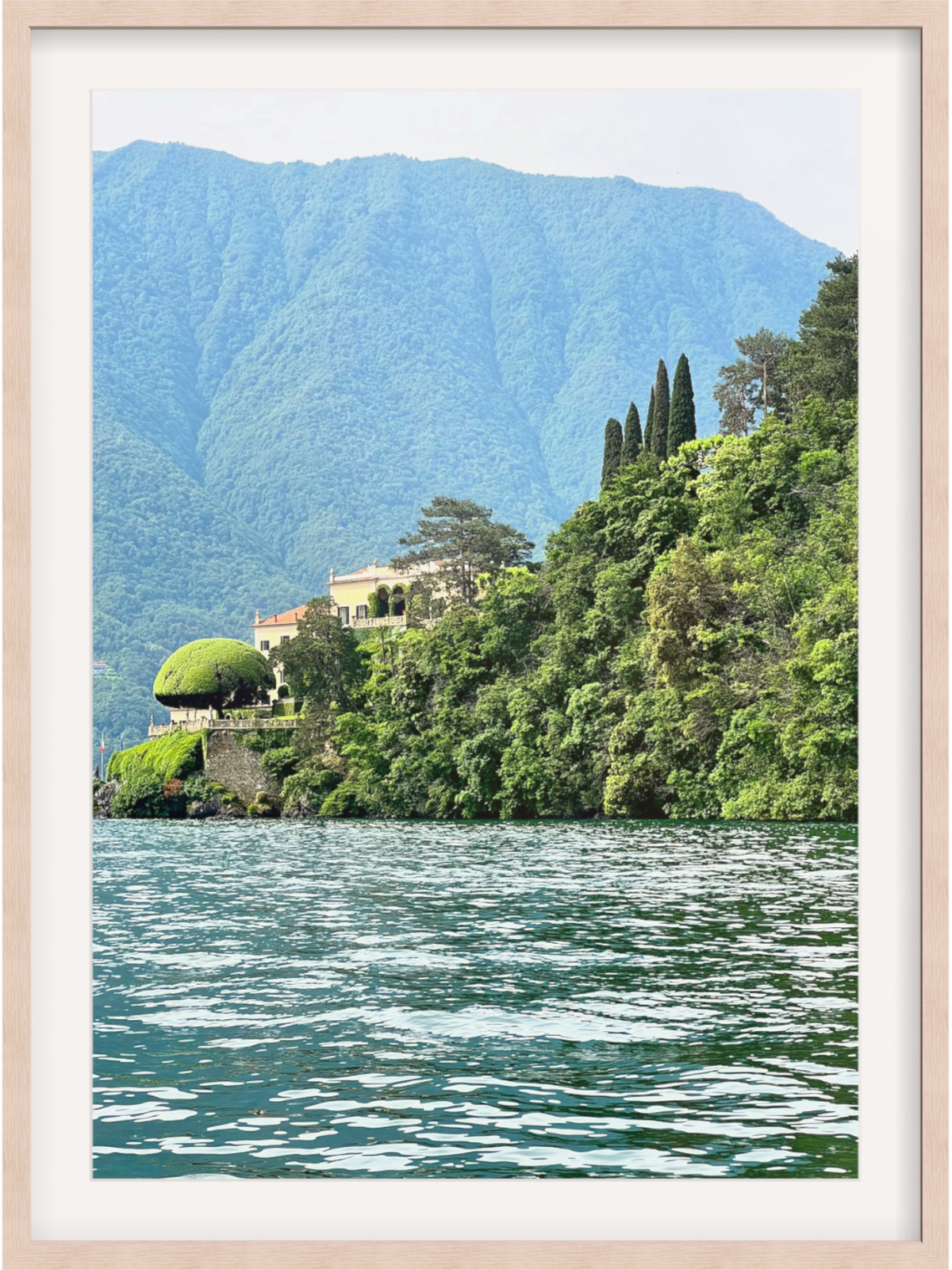 Framed photograph of a scenic view with a house by a lake and mountains.
