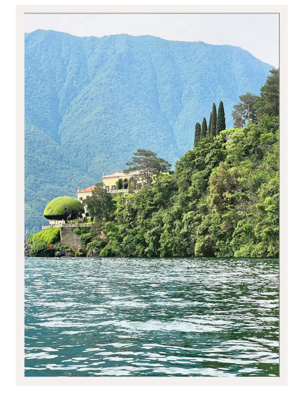 Villa on a hillside overlooking a lake with mountains in the background