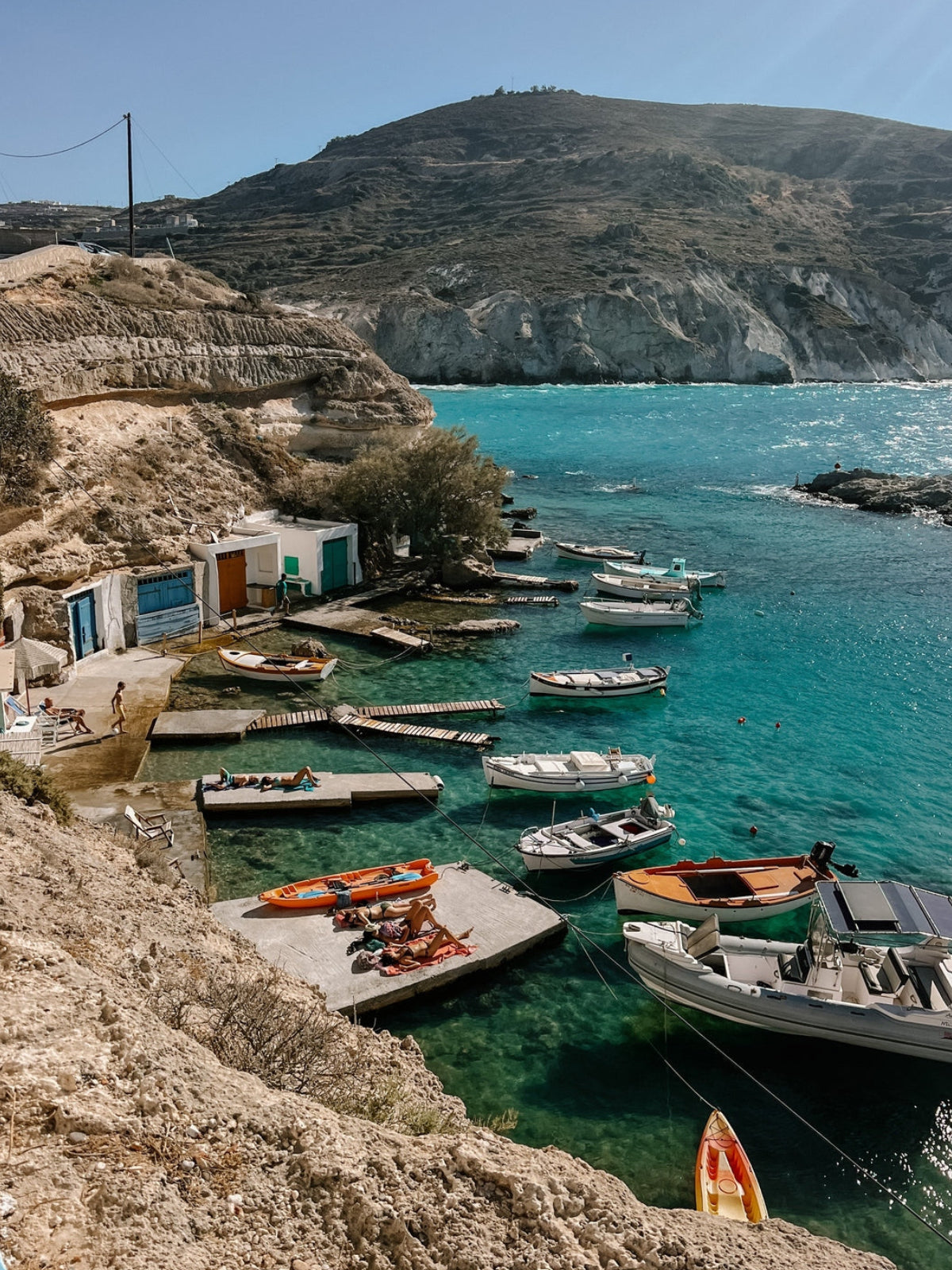Coastal scene with boats docked at a pier near a cliffside.