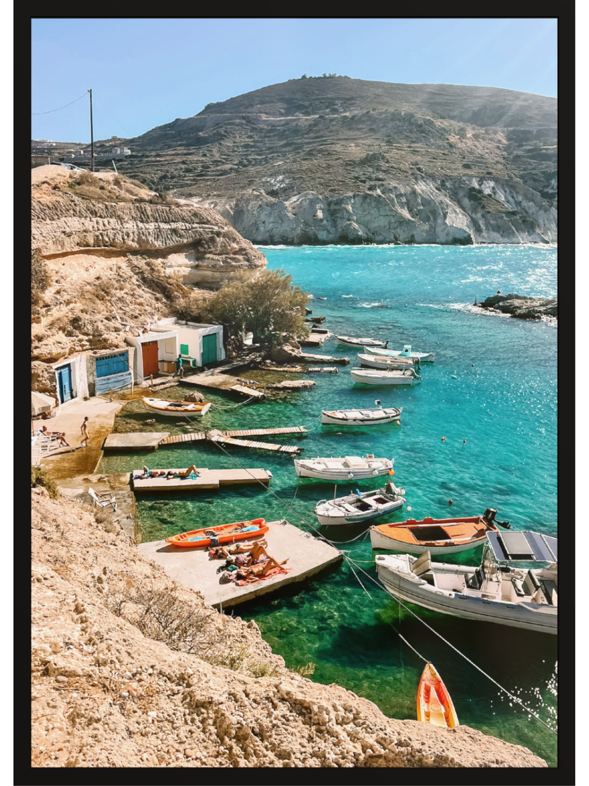 Coastal scene with boats docked at a small harbor surrounded by mountains.