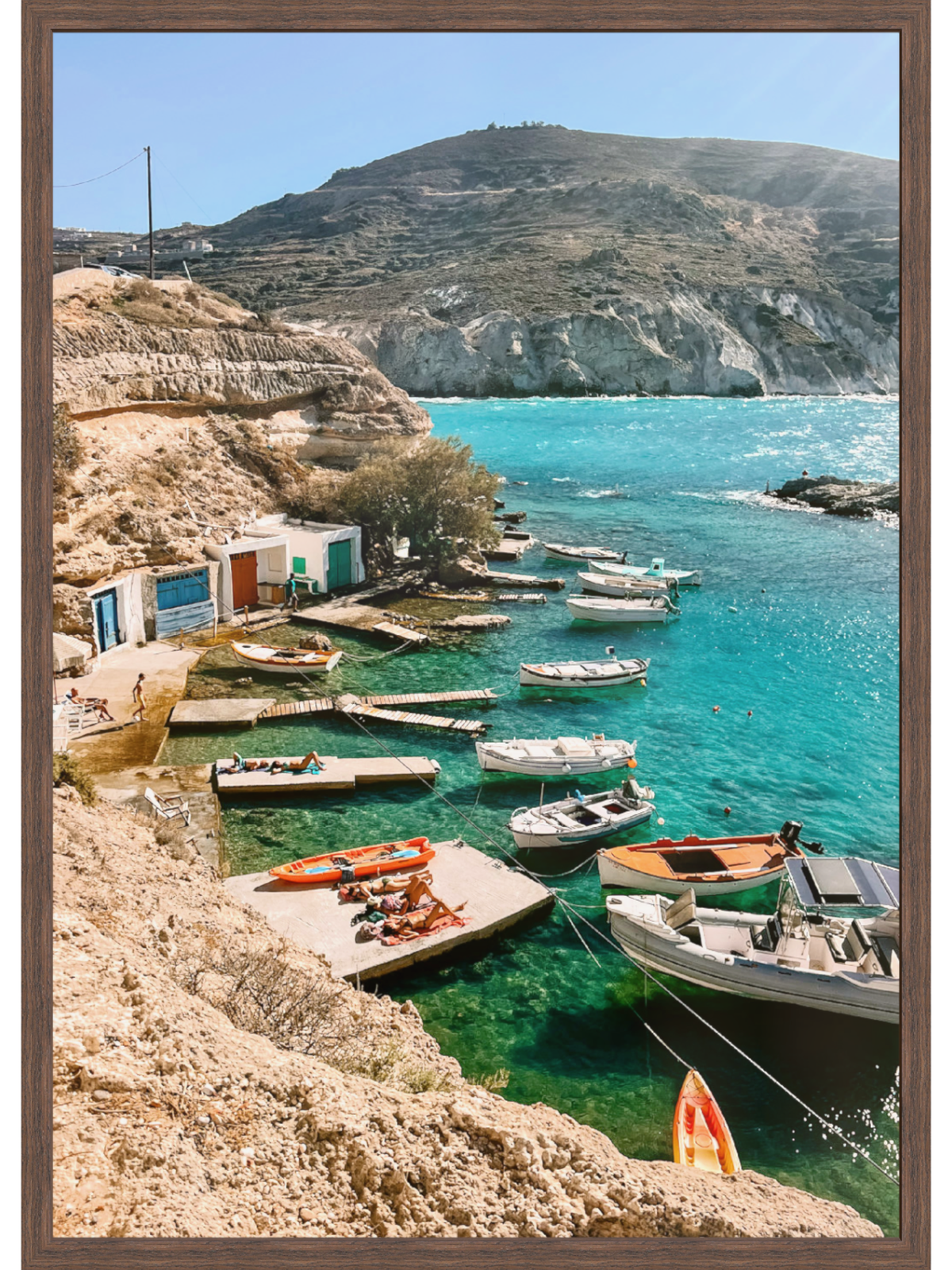 Coastal scene with boats docked near a cliffside, clear blue water, and rocky terrain.