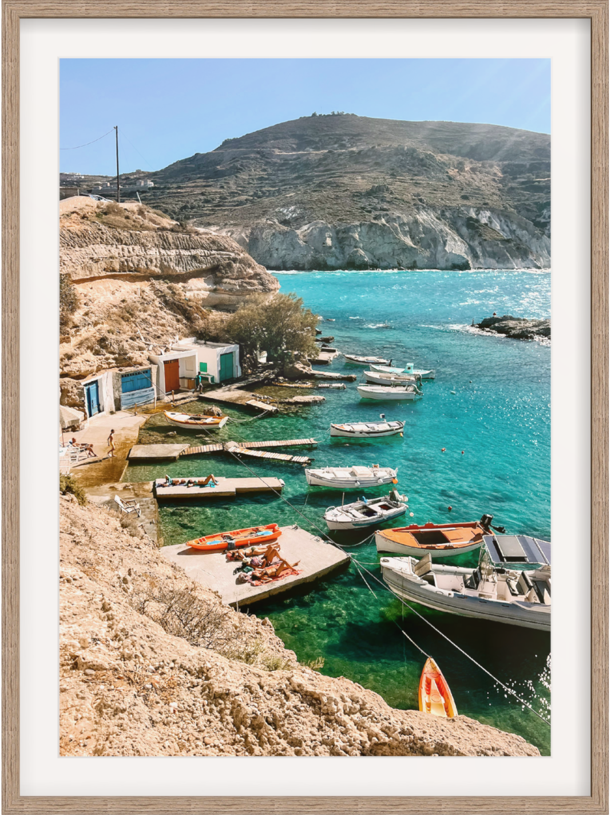 Framed photograph of a coastal scene with boats and cliffs.