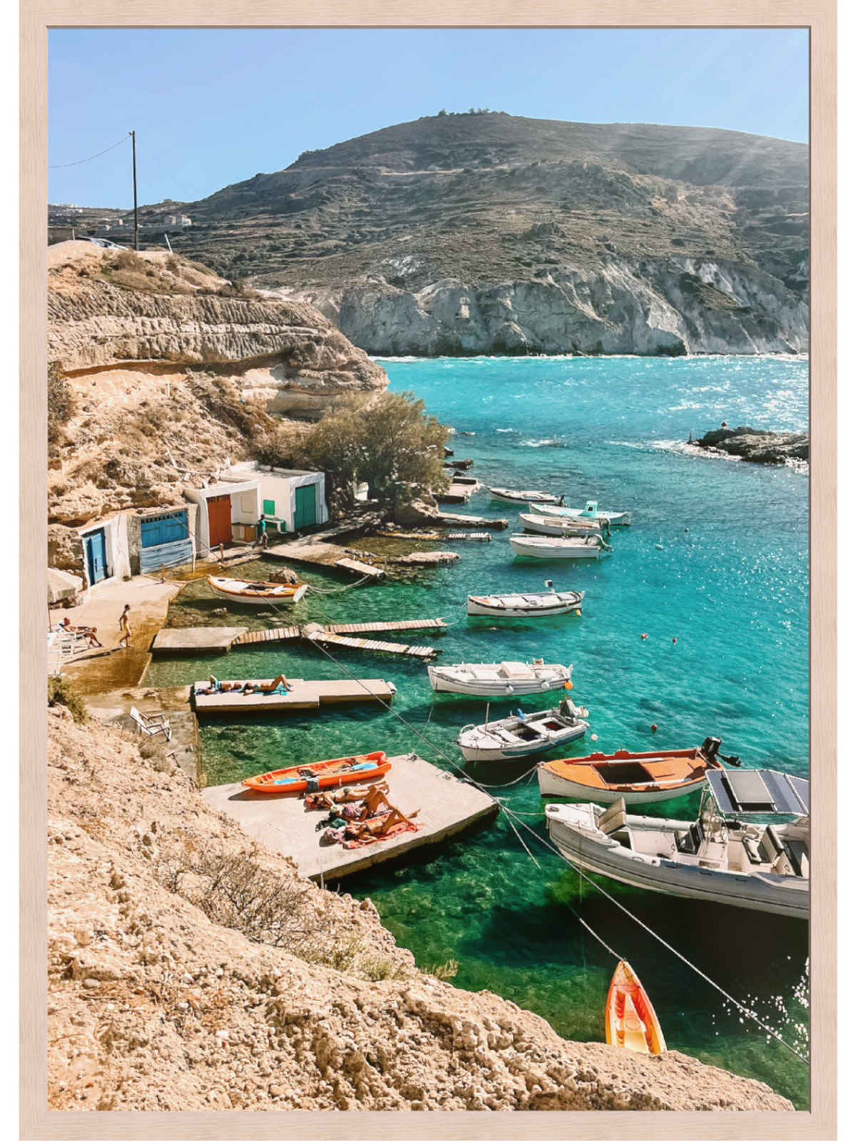 Coastal scene with boats docked at a pier, surrounded by clear blue water and rocky cliffs.