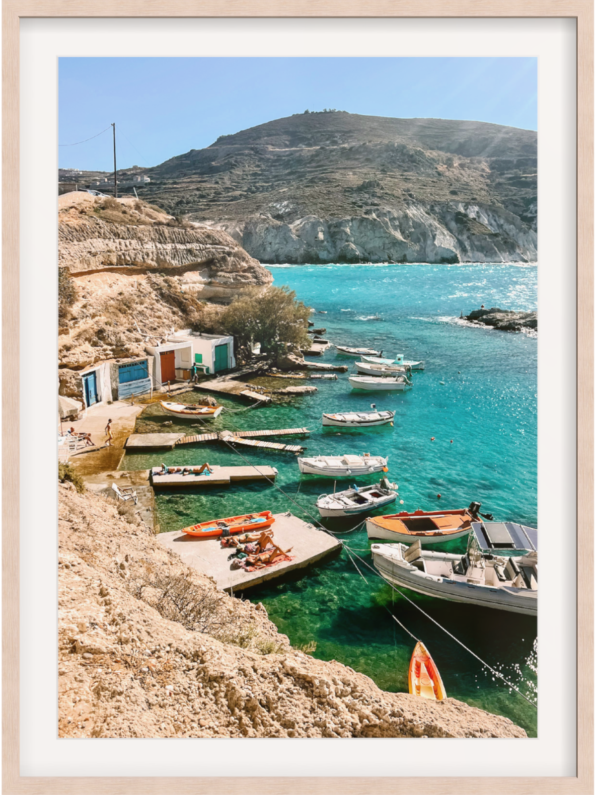 Framed photograph of a coastal scene with boats and cliffs.