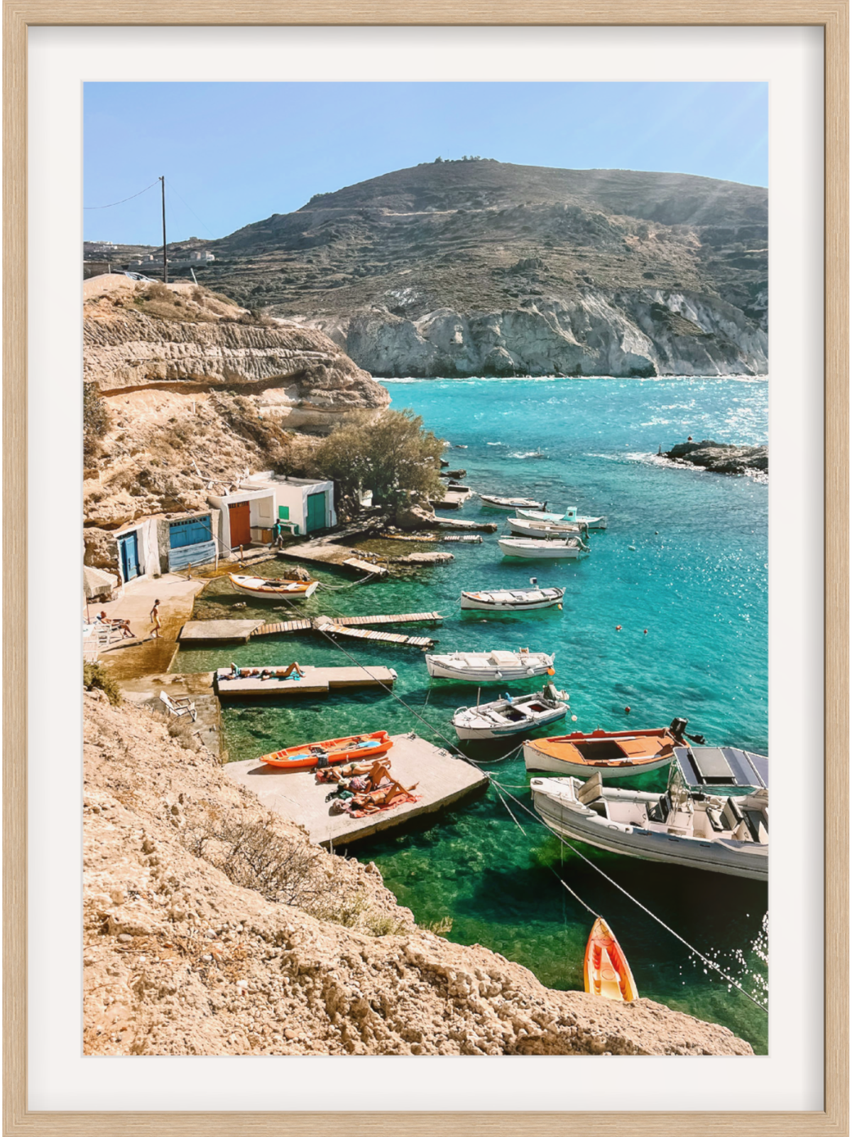 Framed photograph of a coastal scene with boats and cliffs.