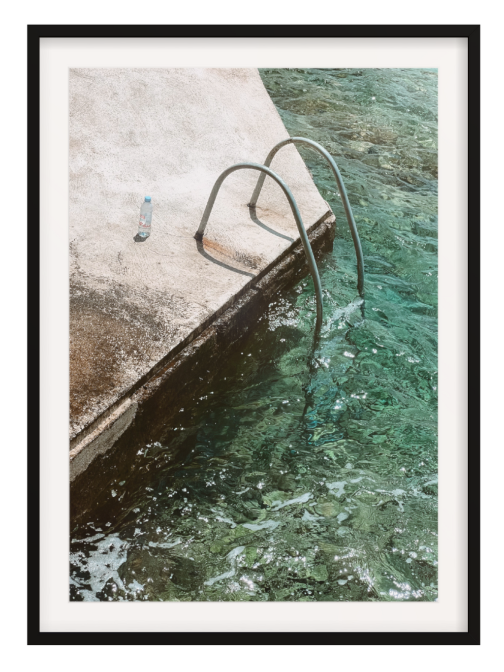 Framed photograph of a pool with a metal ladder and concrete edge.