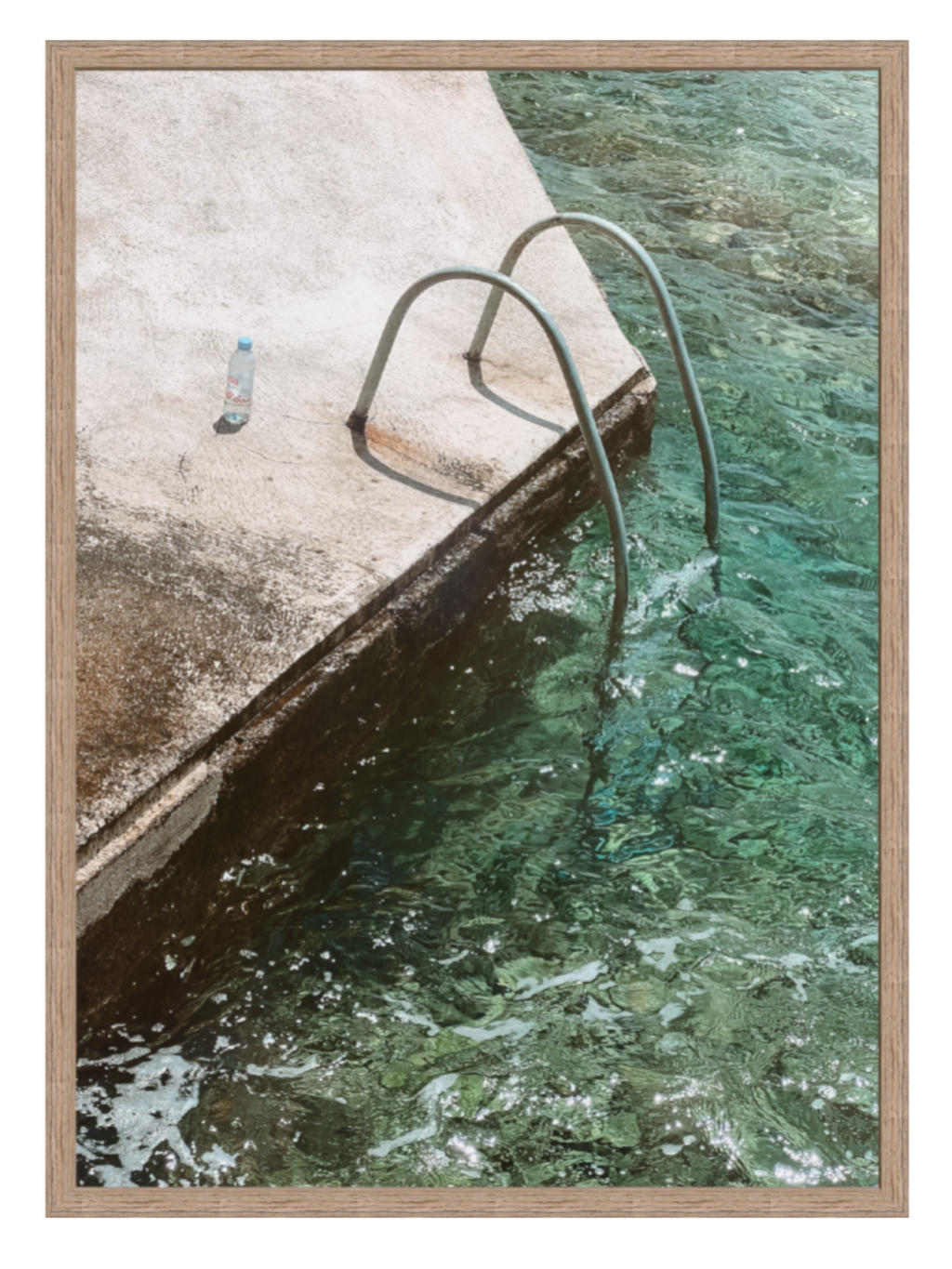 Framed photograph of a pool with a ladder and water edge.