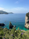 Coastal scene with rocky cliffs, clear blue water, and a few boats.