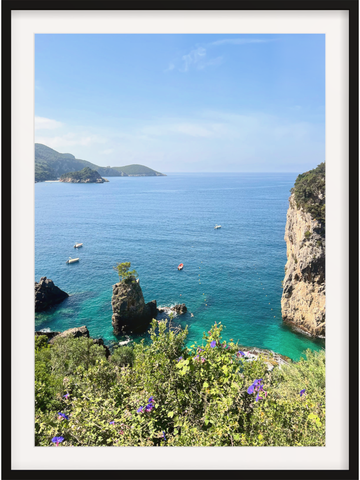 Framed photograph of a coastal landscape with clear blue water, cliffs, and greenery.