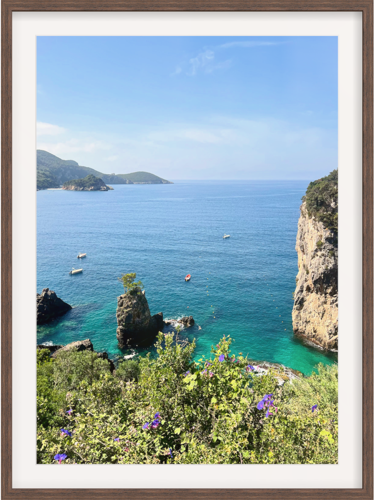 Framed photograph of a coastal scene with clear blue water, rocky cliffs, and greenery.