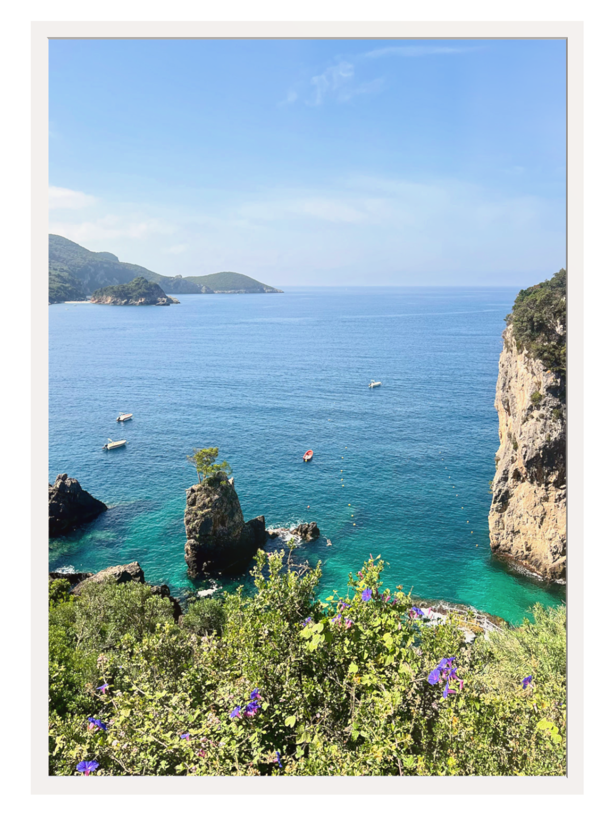 Coastal scene with clear blue water, rocky cliffs, and greenery.