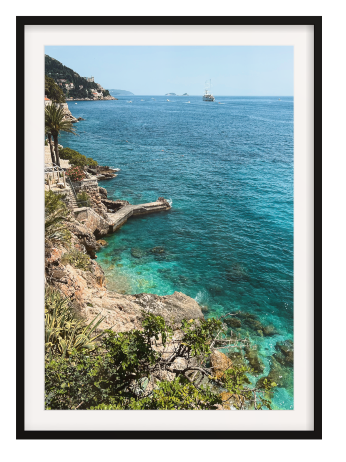 Framed photograph of a coastal scene with clear blue water and rocky cliffs.