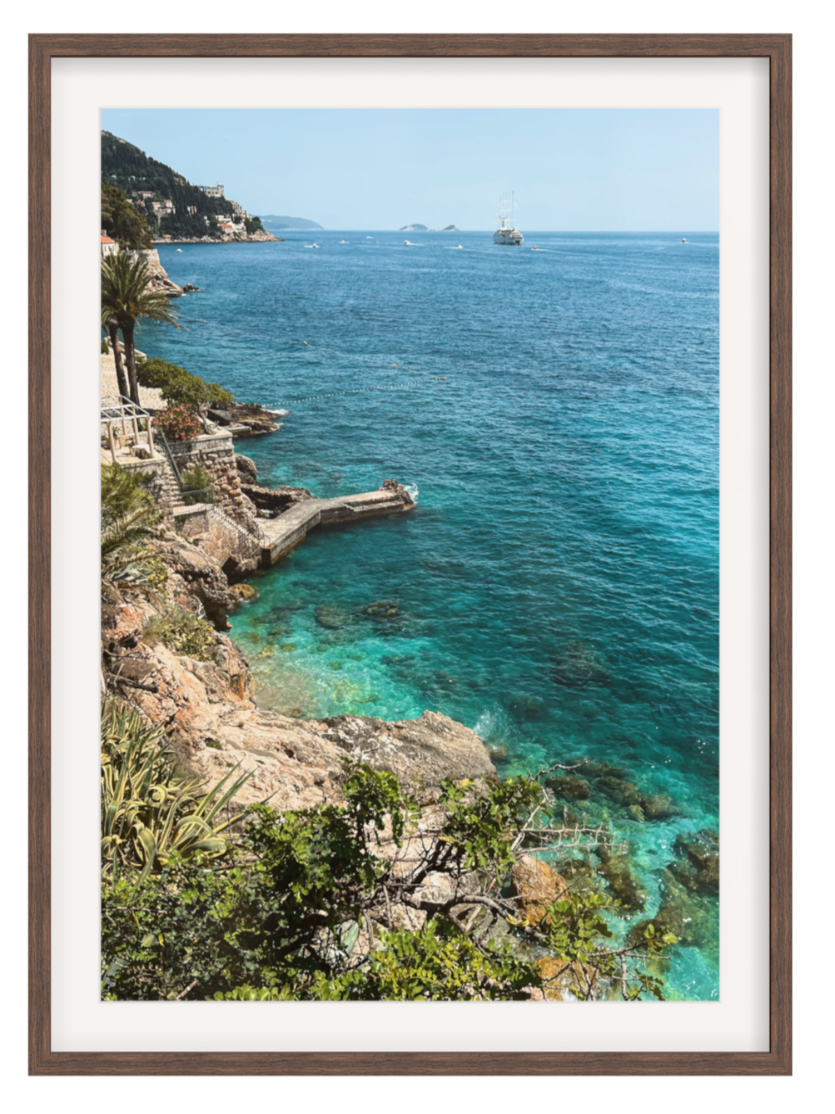 Framed photograph of a coastal scene with clear blue water and rocky cliffs.