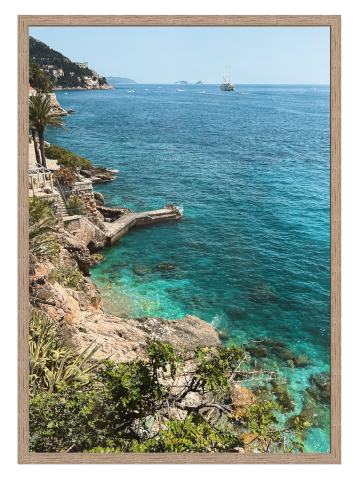 Framed photograph of a coastal scene with clear blue water and rocky cliffs.