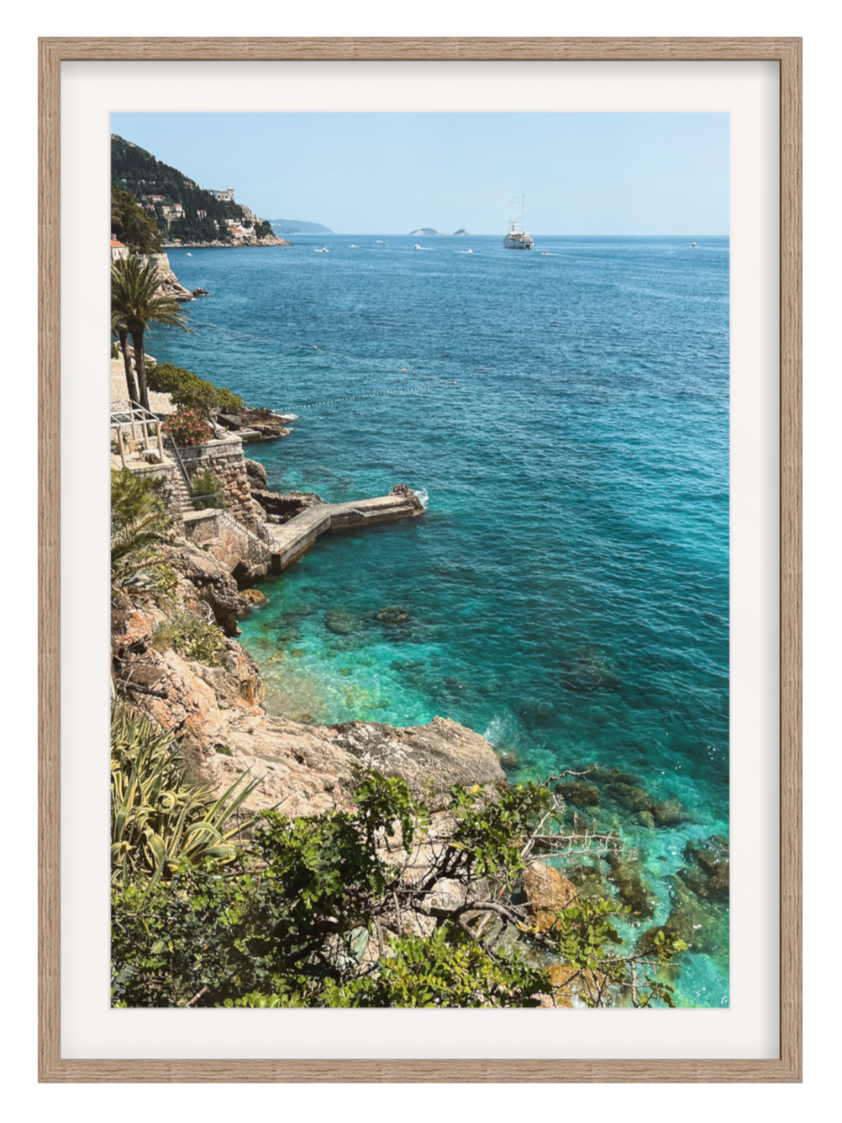 Framed photograph of a coastal scene with clear blue water and rocky cliffs.