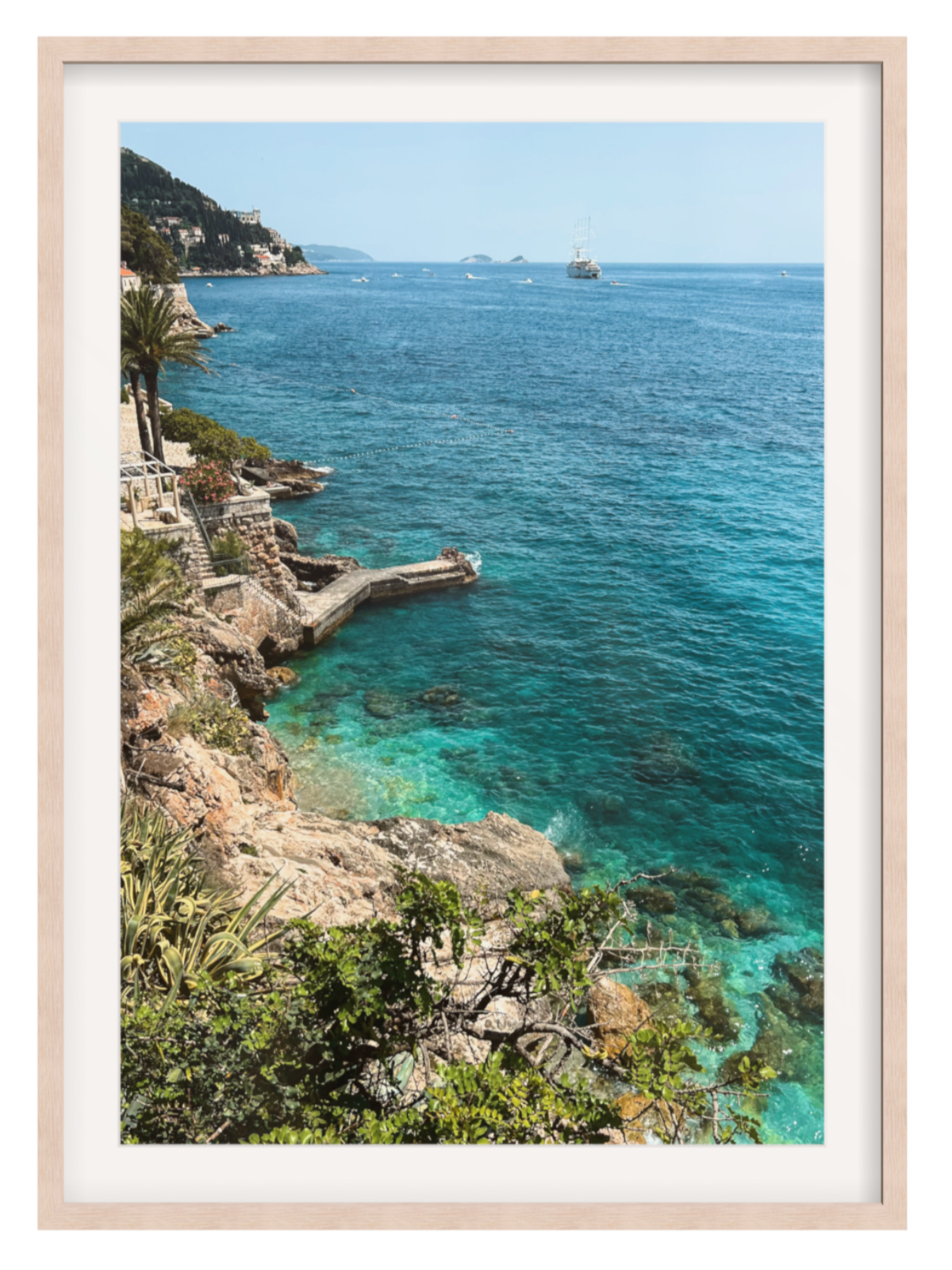 Framed photograph of a coastal scene with clear blue water and rocky cliffs.
