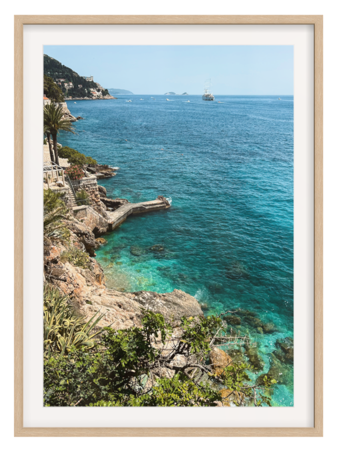 Framed photograph of a coastal landscape with clear blue water and rocky cliffs.