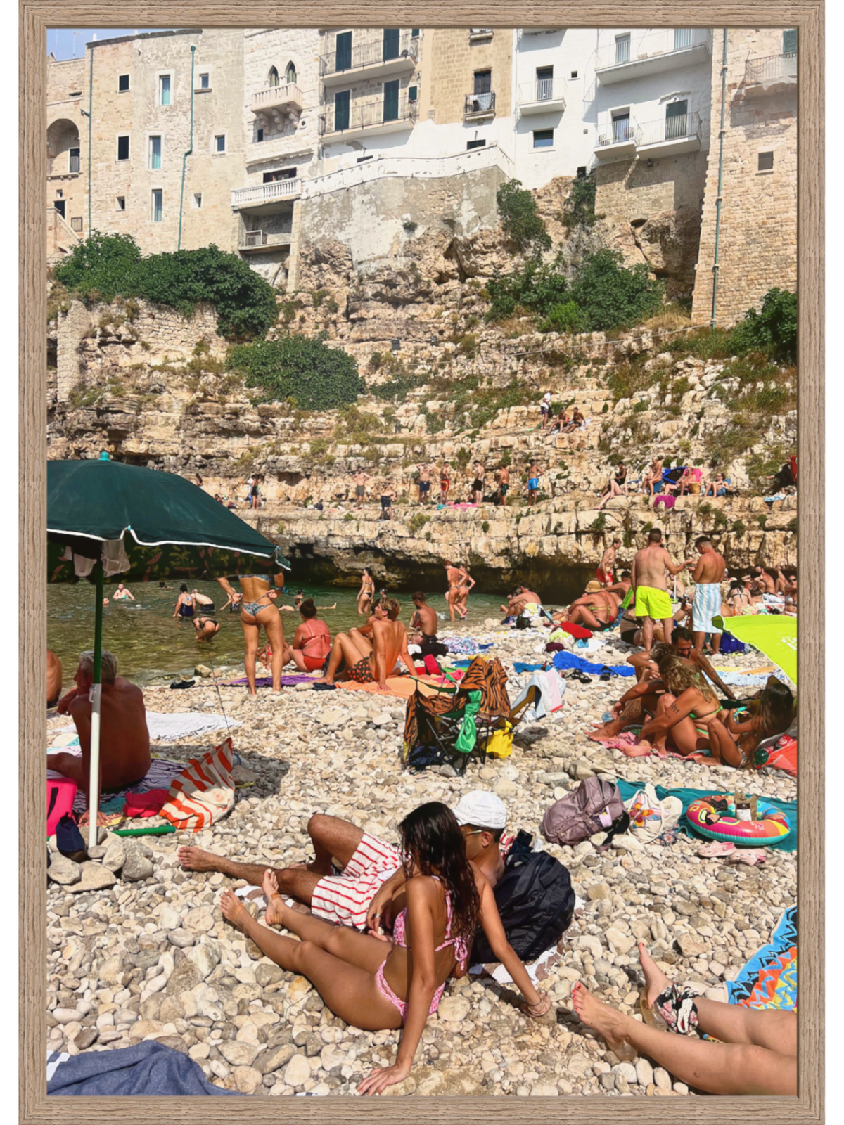 Beach scene with people sunbathing and relaxing on a rocky shoreline.