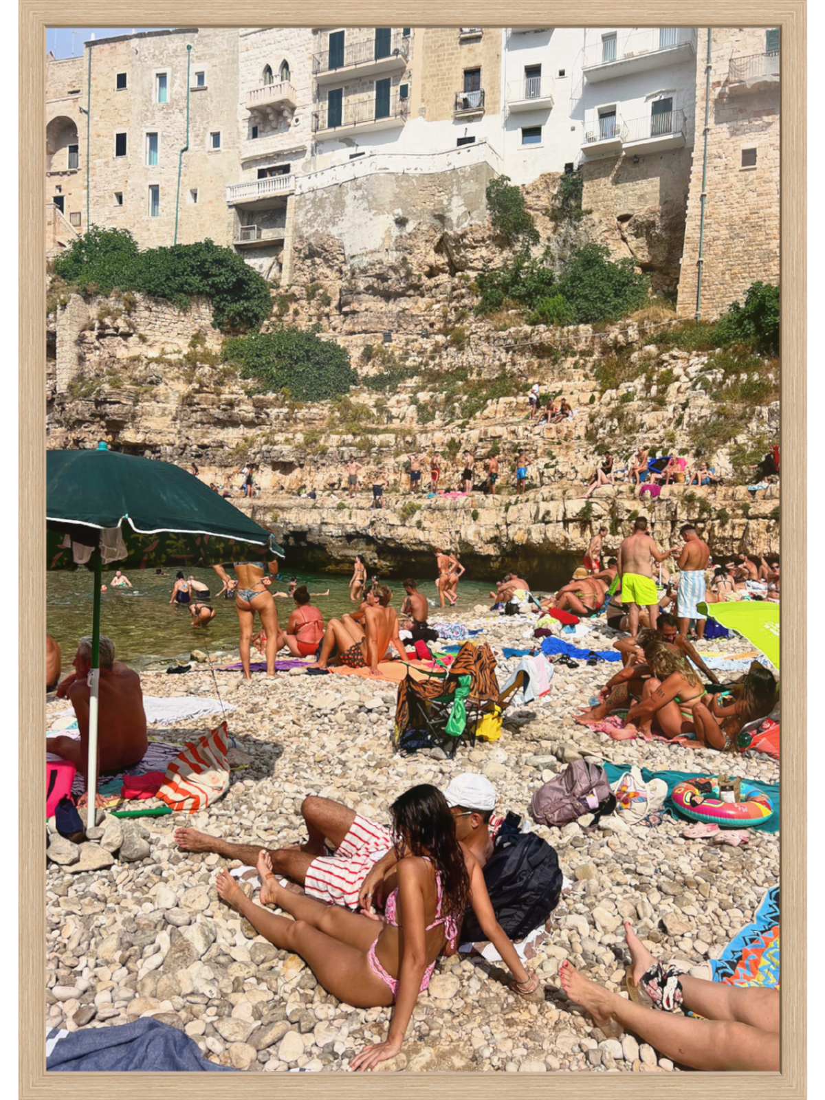 Beach scene with people sunbathing and relaxing near a cliffside building.
