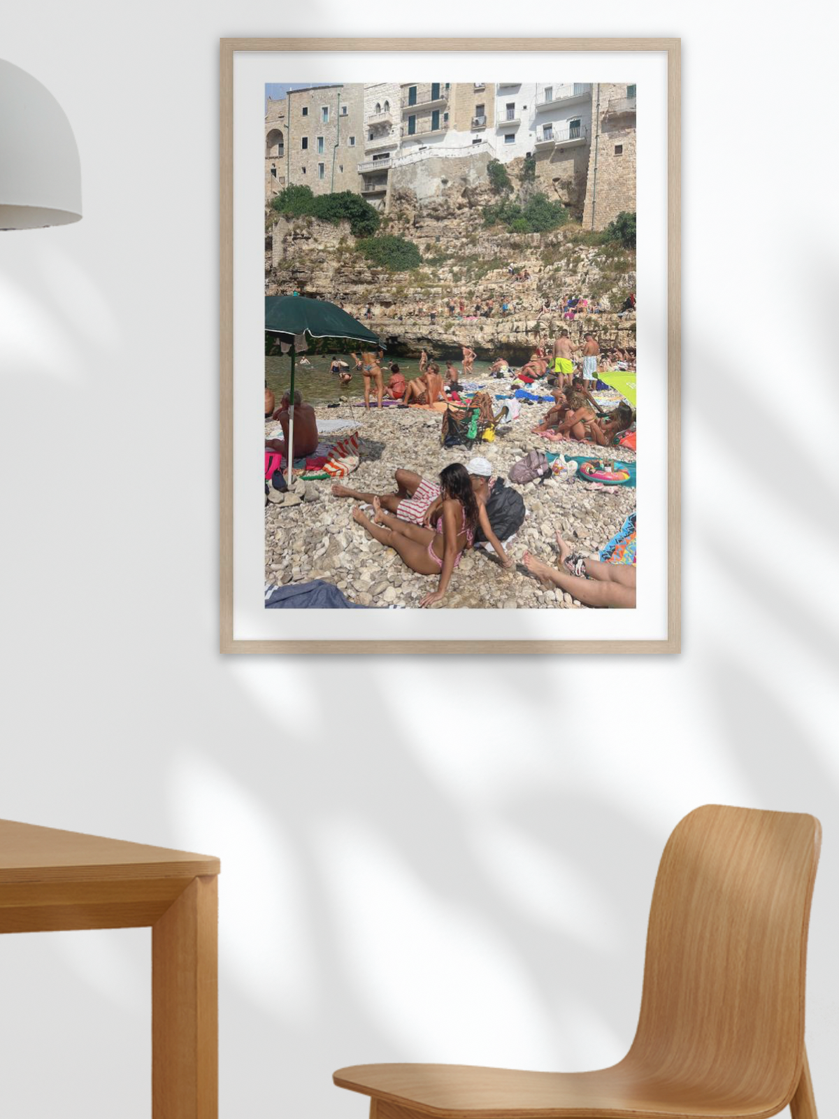 Framed photograph of a beach scene on a white wall with wooden furniture.