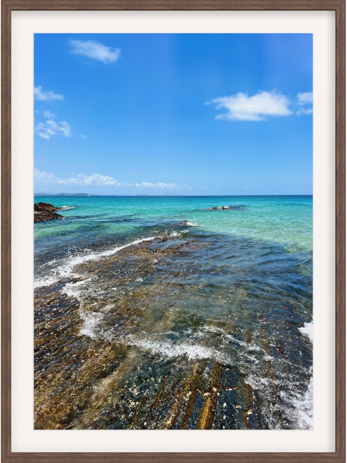 Framed photograph of a coastal scene with clear blue water and sky.