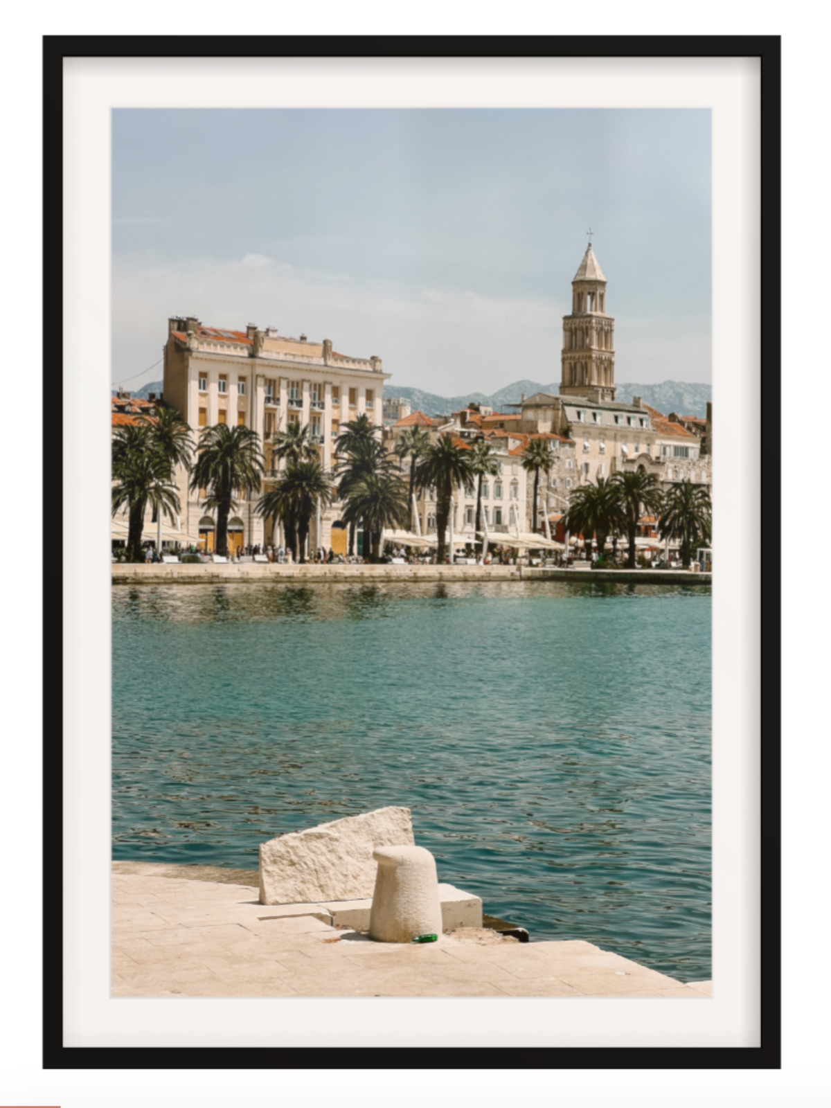 Framed photograph of a coastal cityscape with buildings and palm trees. Split black frame with border