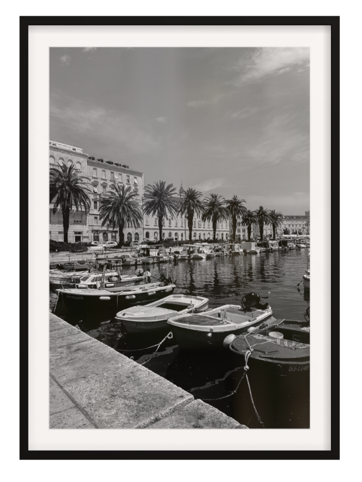 Black and white photograph of a harbor with boats and palm trees.Split boat black frame with border