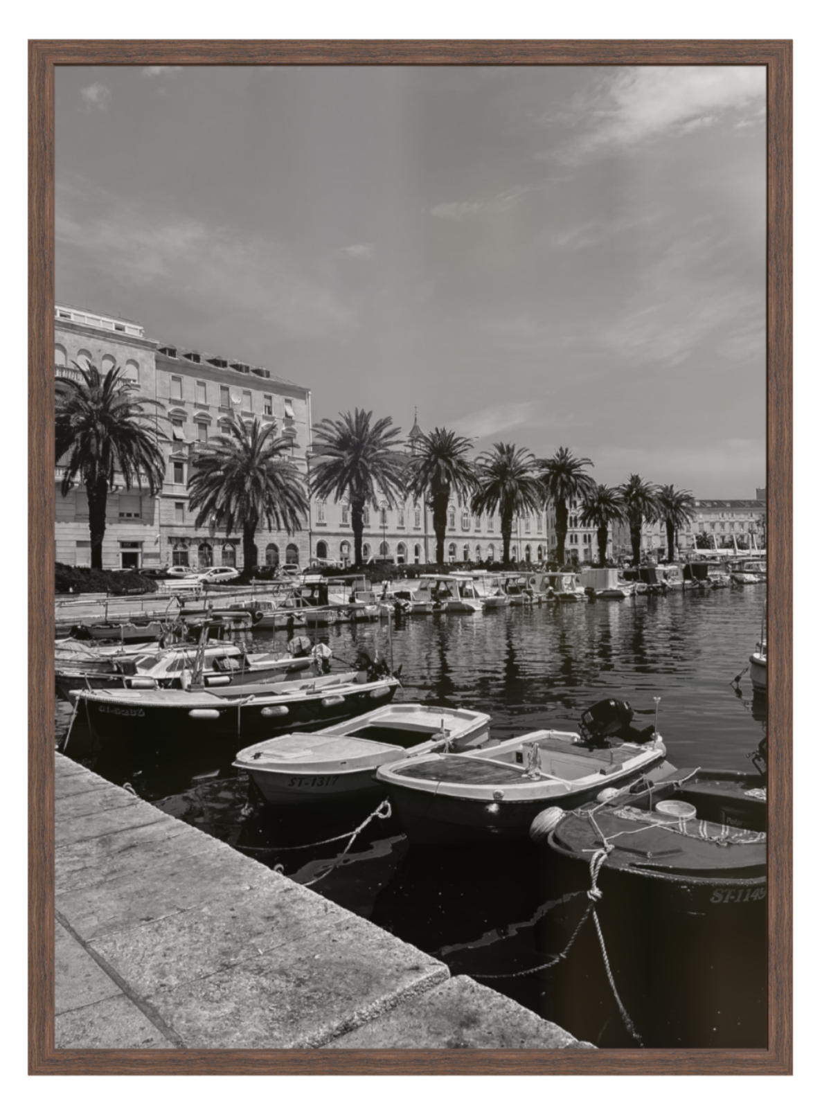 Black and white photograph of a harbor with boats and palm trees, framed in brown.