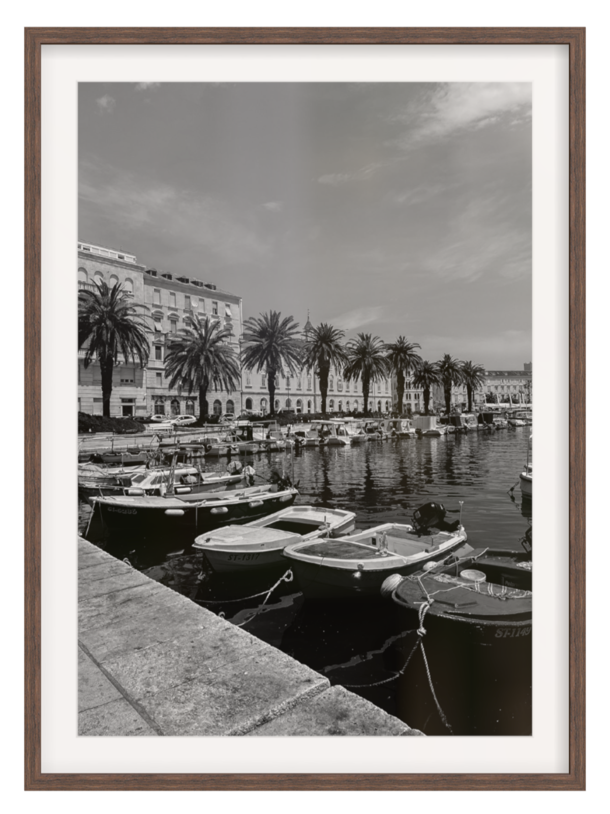 Harbor scene with boats and palm trees in a black and white photograph, framed in brown.