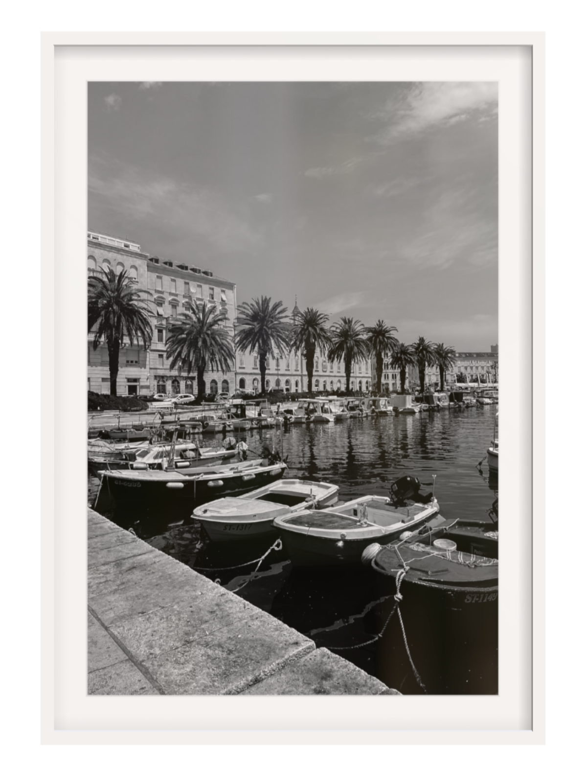 Black and white photograph of a harbor with boats and palm trees. Split boat white frame with border