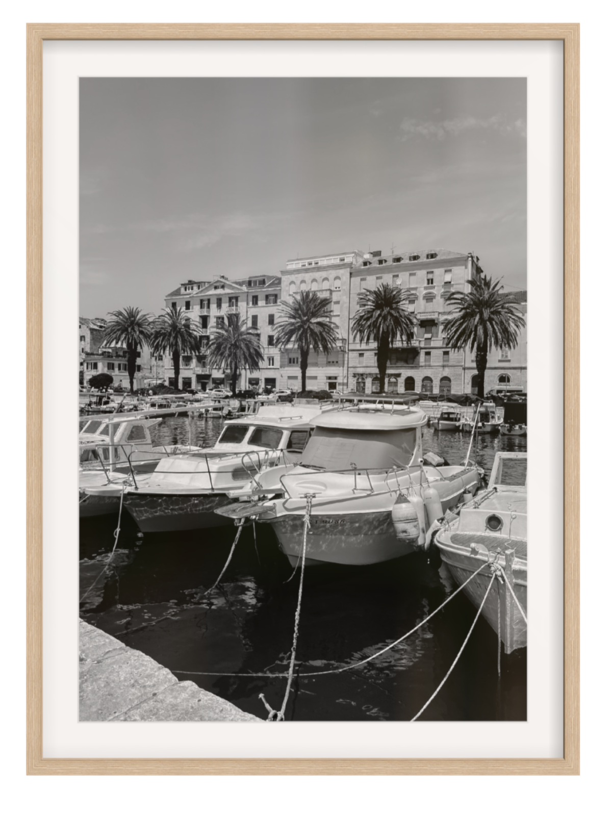 Harbor scene with boats and buildings, framed in a light wood manner. Split harbour oak frame with border