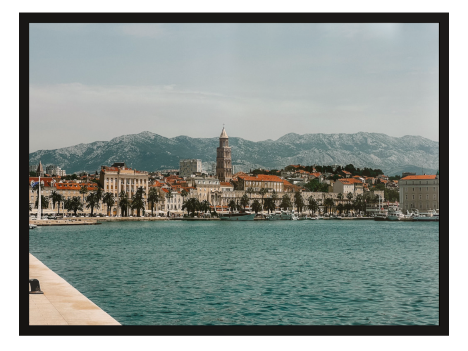 Cityscape with mountains in the background, viewed from a waterfront. Split landscape black frame 