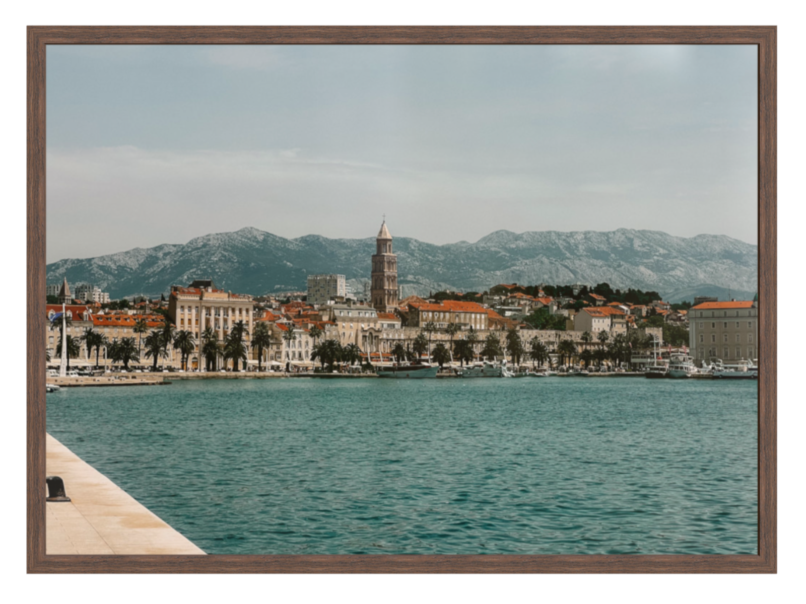 Cityscape with buildings and mountains near a body of water, framed as a picture. Split landscape chocolate frame 